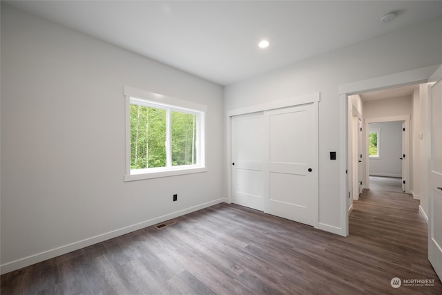 unfurnished bedroom with dark hardwood / wood-style floors and a closet