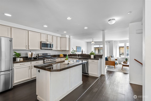 kitchen with stainless steel appliances, dark hardwood / wood-style floors, a kitchen island, sink, and kitchen peninsula