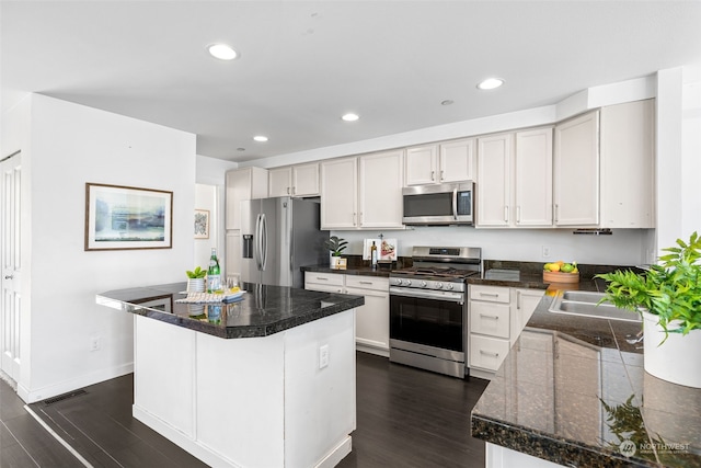 kitchen featuring dark hardwood / wood-style floors, white cabinetry, appliances with stainless steel finishes, a center island, and sink