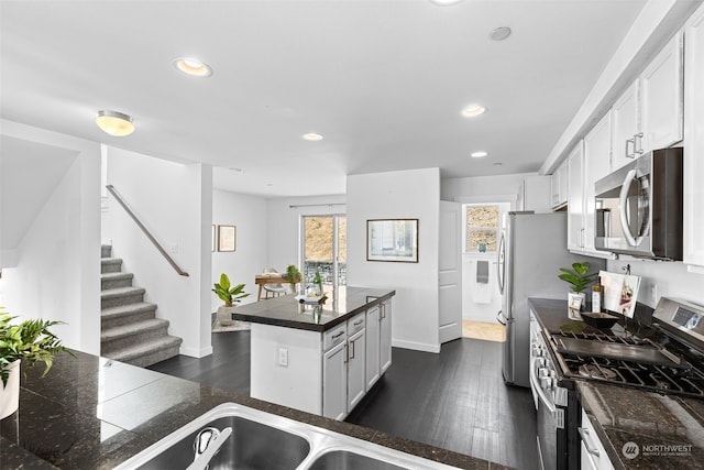 kitchen featuring dark hardwood / wood-style floors, stainless steel appliances, a center island, and white cabinetry