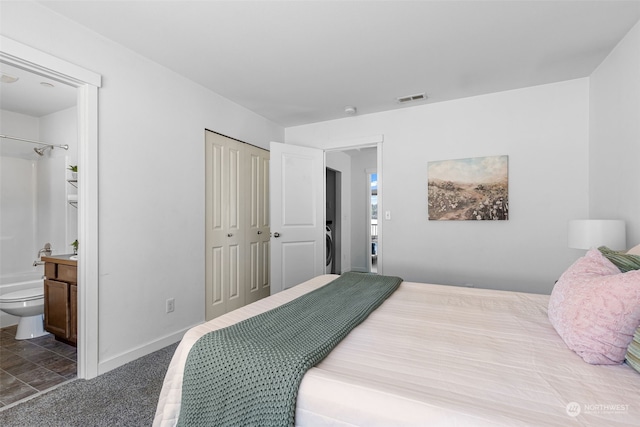 carpeted bedroom with ensuite bath and a closet