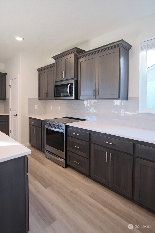 kitchen featuring dark brown cabinets, stainless steel appliances, light hardwood / wood-style flooring, and decorative backsplash