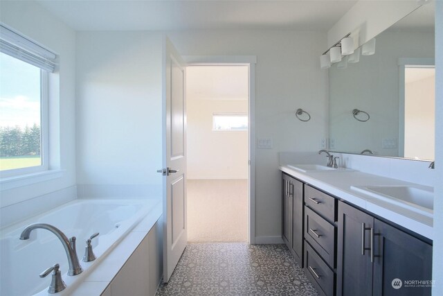 bathroom with tile patterned floors, plenty of natural light, vanity, and tiled bath