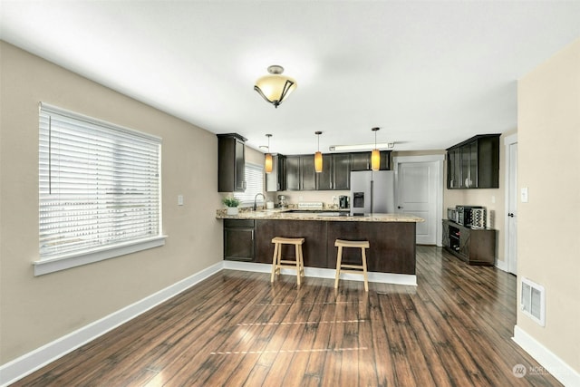 kitchen featuring hanging light fixtures, stainless steel fridge with ice dispenser, dark hardwood / wood-style floors, and kitchen peninsula