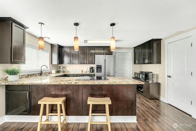 kitchen with sink, stainless steel fridge with ice dispenser, dark brown cabinets, hanging light fixtures, and kitchen peninsula