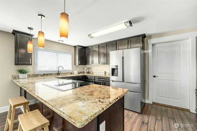 kitchen featuring stainless steel fridge with ice dispenser, decorative light fixtures, black electric stovetop, dark brown cabinetry, and kitchen peninsula