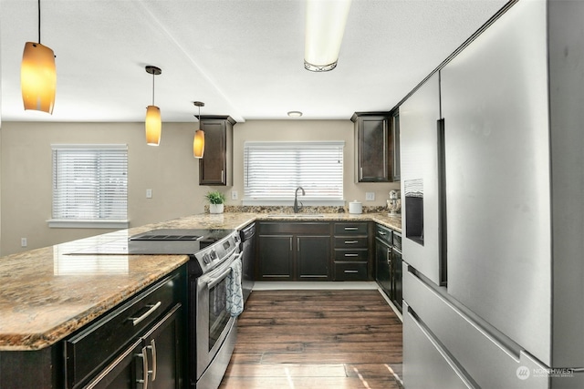 kitchen featuring stainless steel appliances, sink, dark wood-type flooring, and decorative light fixtures