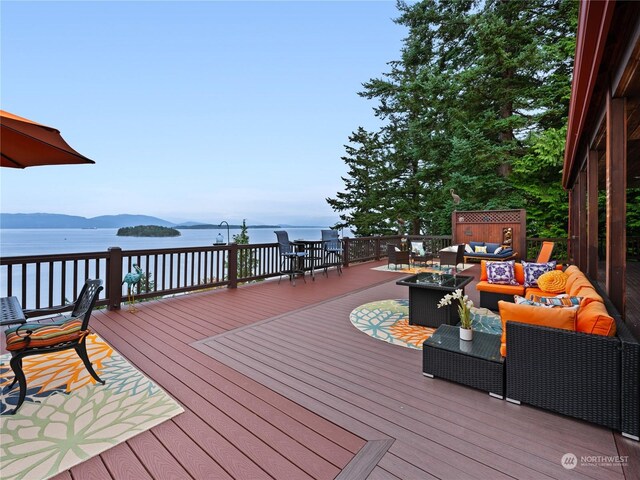 wooden terrace with an outdoor living space with a fire pit and a water and mountain view