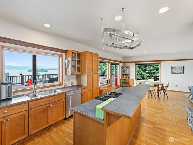 kitchen with a kitchen island, brown cabinets, a sink, and stainless steel dishwasher