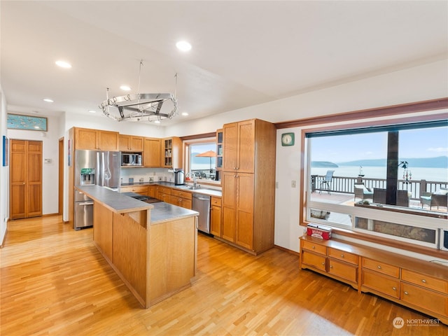 kitchen with stainless steel appliances, a center island, a sink, and light wood finished floors