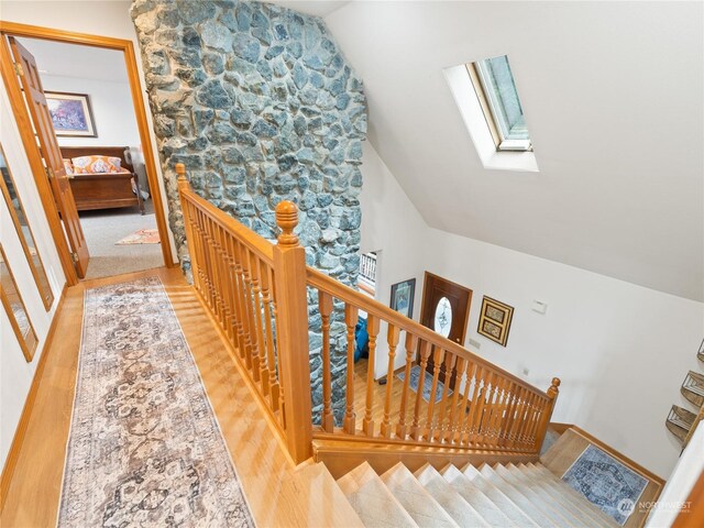 stairs featuring lofted ceiling with skylight and wood finished floors