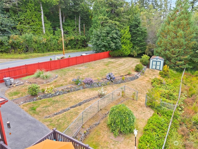 view of yard featuring an outbuilding, a shed, fence, and a vegetable garden