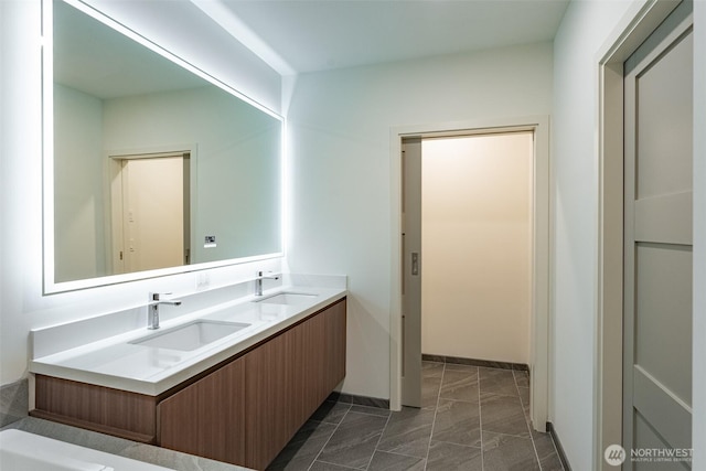 bathroom featuring double vanity, a sink, and baseboards