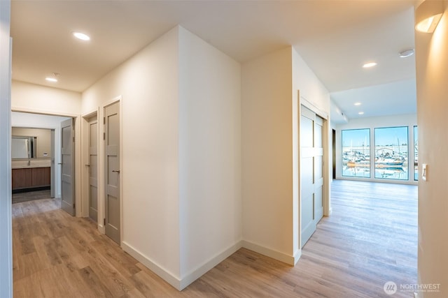 hall featuring light wood-style floors, recessed lighting, and baseboards