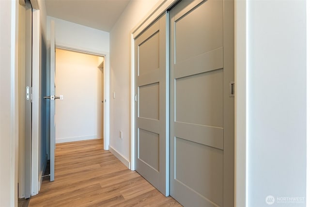 corridor with light wood-type flooring and baseboards