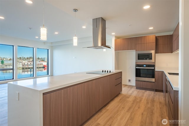 kitchen with modern cabinets, oven, island exhaust hood, built in microwave, and light countertops