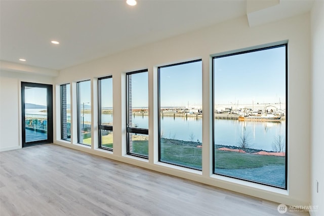 unfurnished room featuring a water view, light wood finished floors, and recessed lighting