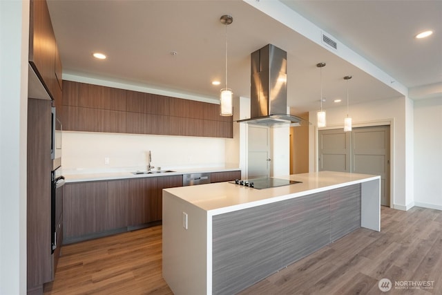 kitchen with light countertops, a sink, island range hood, and modern cabinets