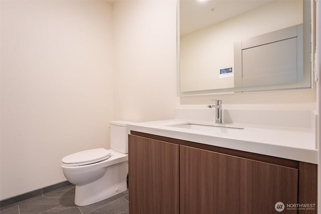 half bath with baseboards, vanity, toilet, and tile patterned floors