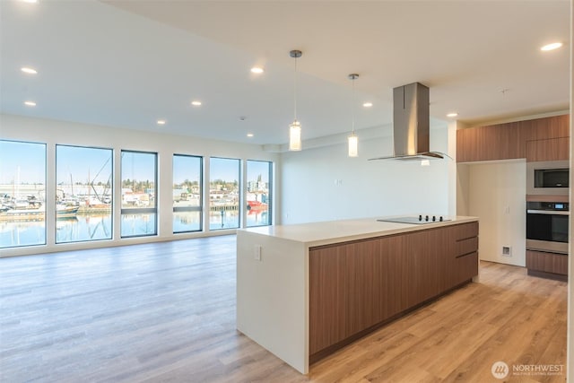 kitchen featuring brown cabinets, light countertops, appliances with stainless steel finishes, island range hood, and modern cabinets