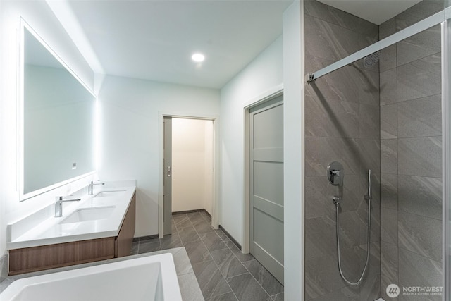 full bath with a tile shower, a sink, and recessed lighting