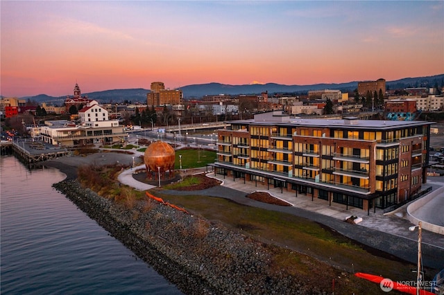 aerial view at dusk with a city view and a water and mountain view