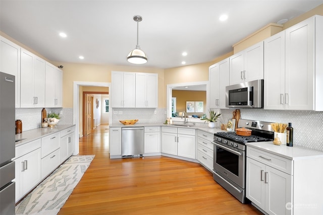 kitchen featuring light wood-type flooring, appliances with stainless steel finishes, sink, and decorative backsplash