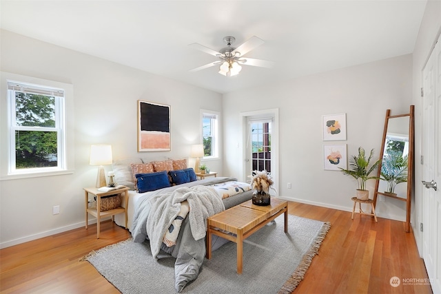 bedroom with multiple windows, light wood-type flooring, access to outside, and ceiling fan