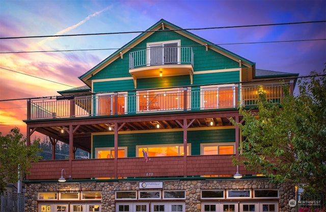 back house at dusk featuring a balcony