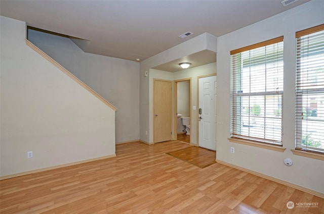 empty room featuring baseboards, light wood-style flooring, visible vents, and a wealth of natural light