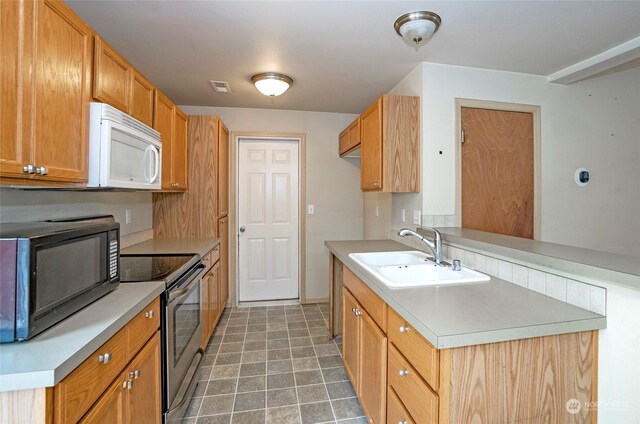 kitchen with stainless steel electric range oven, light countertops, white microwave, a sink, and black microwave