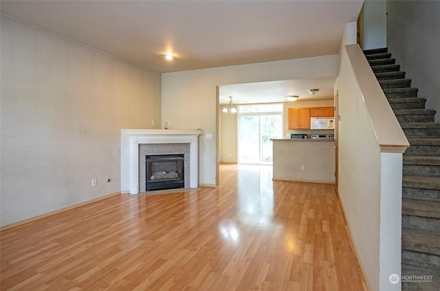 unfurnished living room featuring stairs, light wood finished floors, and a fireplace