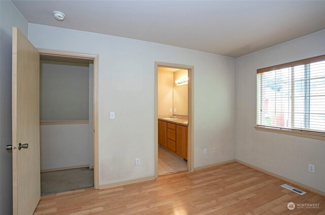 unfurnished bedroom with light wood finished floors, baseboards, and visible vents