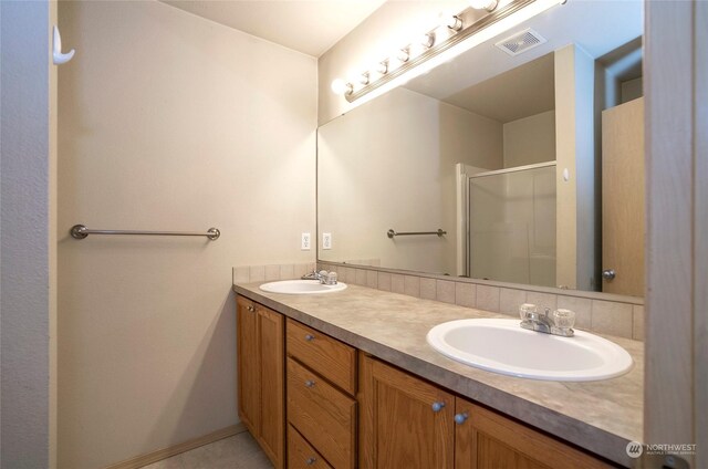 full bathroom featuring double vanity, a shower stall, visible vents, and a sink