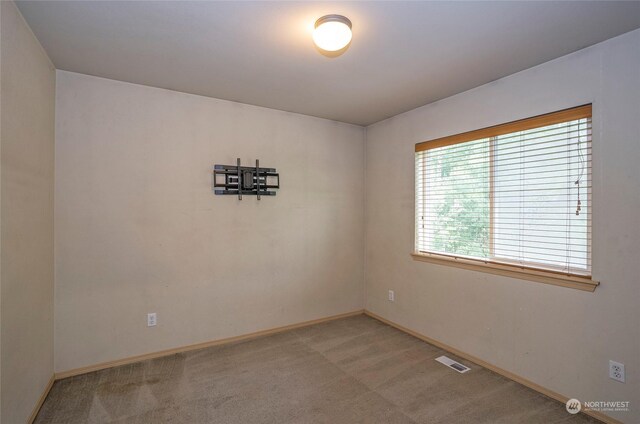 spare room featuring visible vents, light carpet, and baseboards