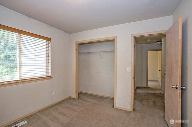 unfurnished bedroom featuring baseboards, visible vents, a closet, and light colored carpet