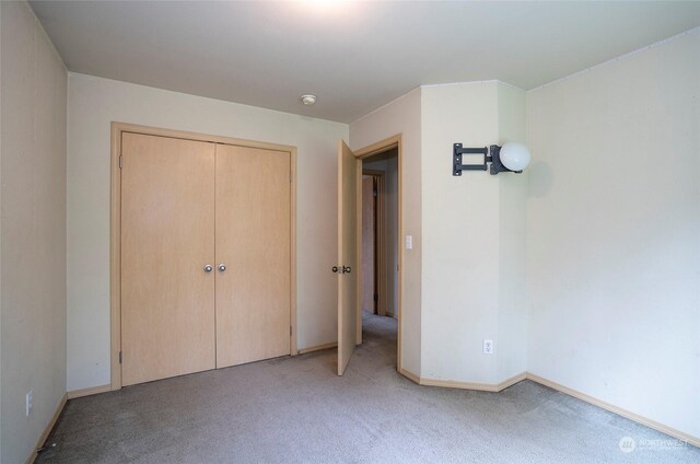 unfurnished bedroom with a closet, light carpet, and baseboards