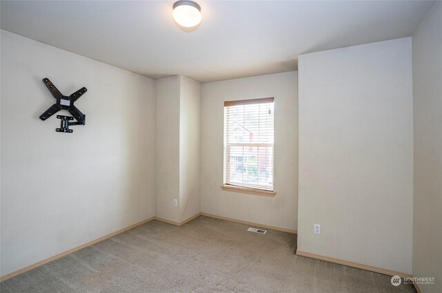 unfurnished room featuring carpet, visible vents, and baseboards