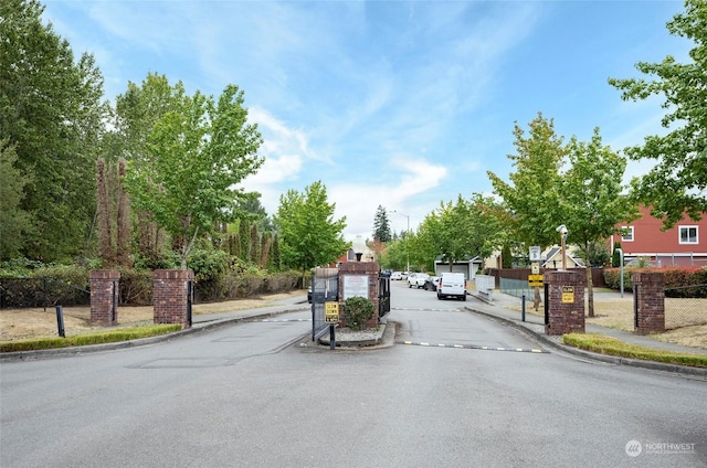 view of street featuring a gate, curbs, sidewalks, and a gated entry