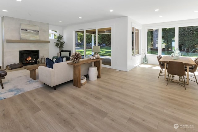 living room with baseboards, light wood finished floors, a fireplace, and recessed lighting