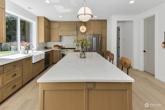 kitchen with a kitchen island, custom exhaust hood, stainless steel appliances, light wood-style floors, and a sink