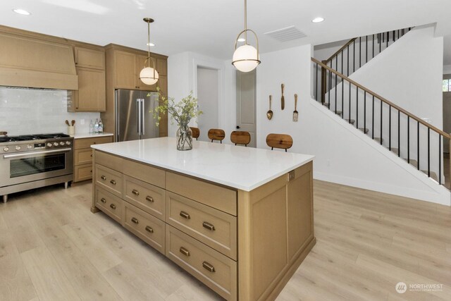 kitchen featuring visible vents, hanging light fixtures, appliances with stainless steel finishes, light wood finished floors, and custom range hood