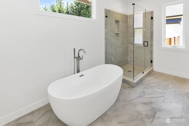 bathroom with marble finish floor, baseboards, a soaking tub, and a stall shower