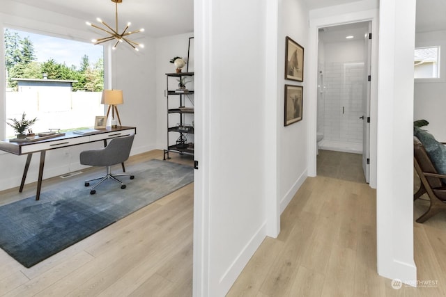 home office with light wood-type flooring, baseboards, and an inviting chandelier