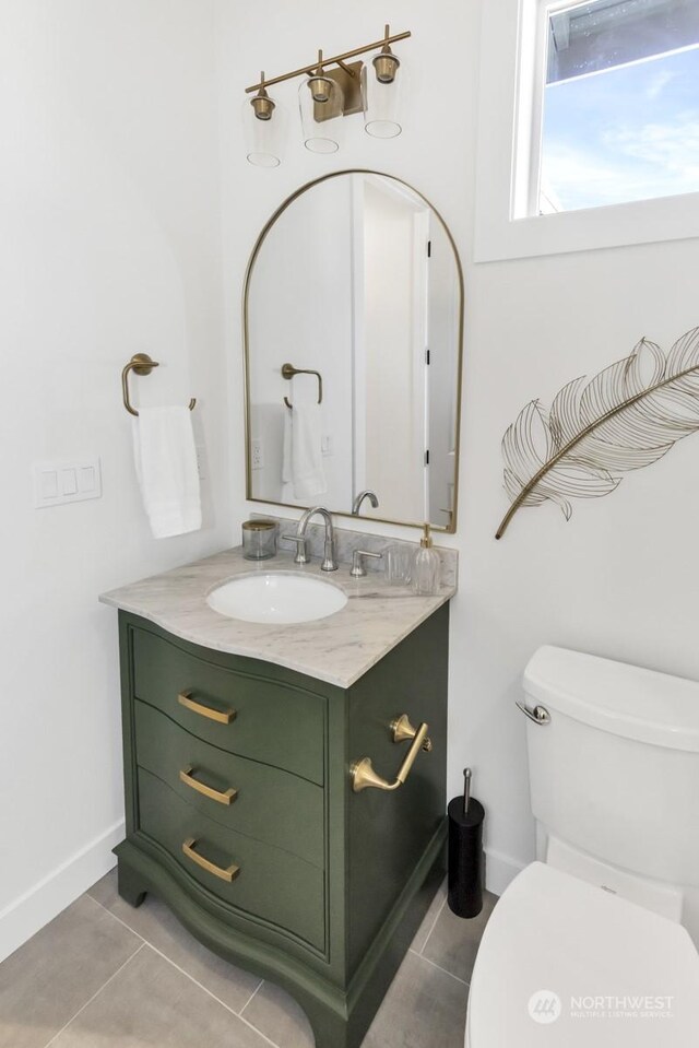 bathroom with toilet, baseboards, vanity, and tile patterned floors