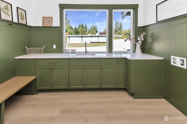 kitchen featuring light countertops, light wood finished floors, a sink, and green cabinetry