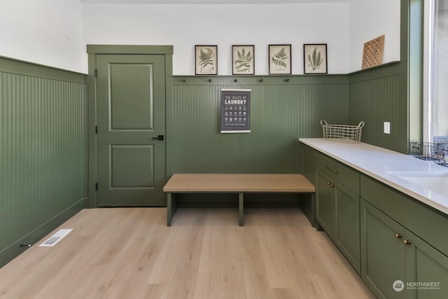 mudroom with light wood-style flooring, visible vents, a sink, and wainscoting