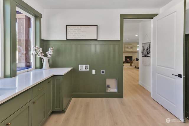 laundry area with hookup for a washing machine, a wainscoted wall, light wood-style floors, cabinet space, and electric dryer hookup