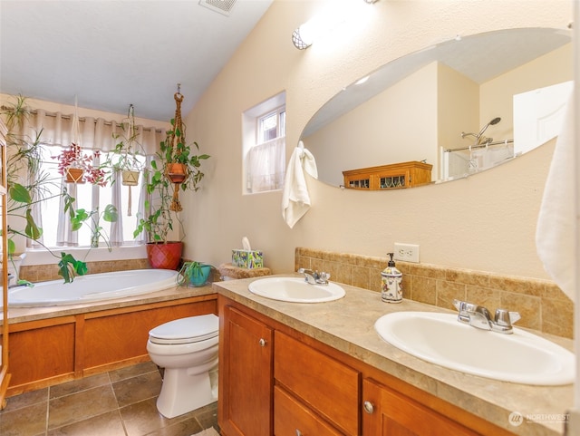 bathroom featuring double vanity, a tub, lofted ceiling, toilet, and tile patterned flooring