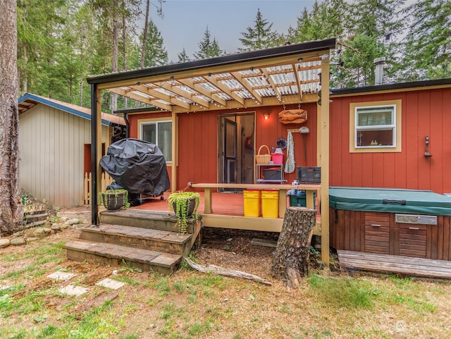 back of house with a pergola and a hot tub